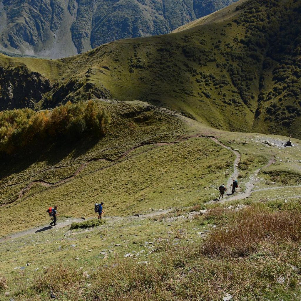 Туристы на пеших маршрутах в горах в районе Троицкой церкви (Гергети) в Казбеги