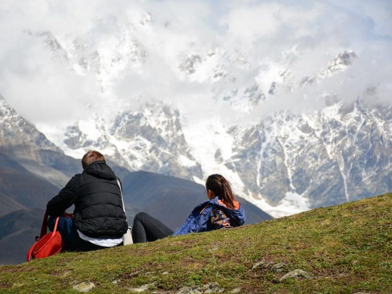 Пара туристов смотрит на гору в Местии, Грузия