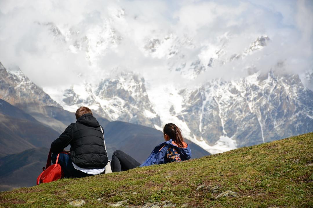 Пара туристов смотрит на гору в Местии, Грузия